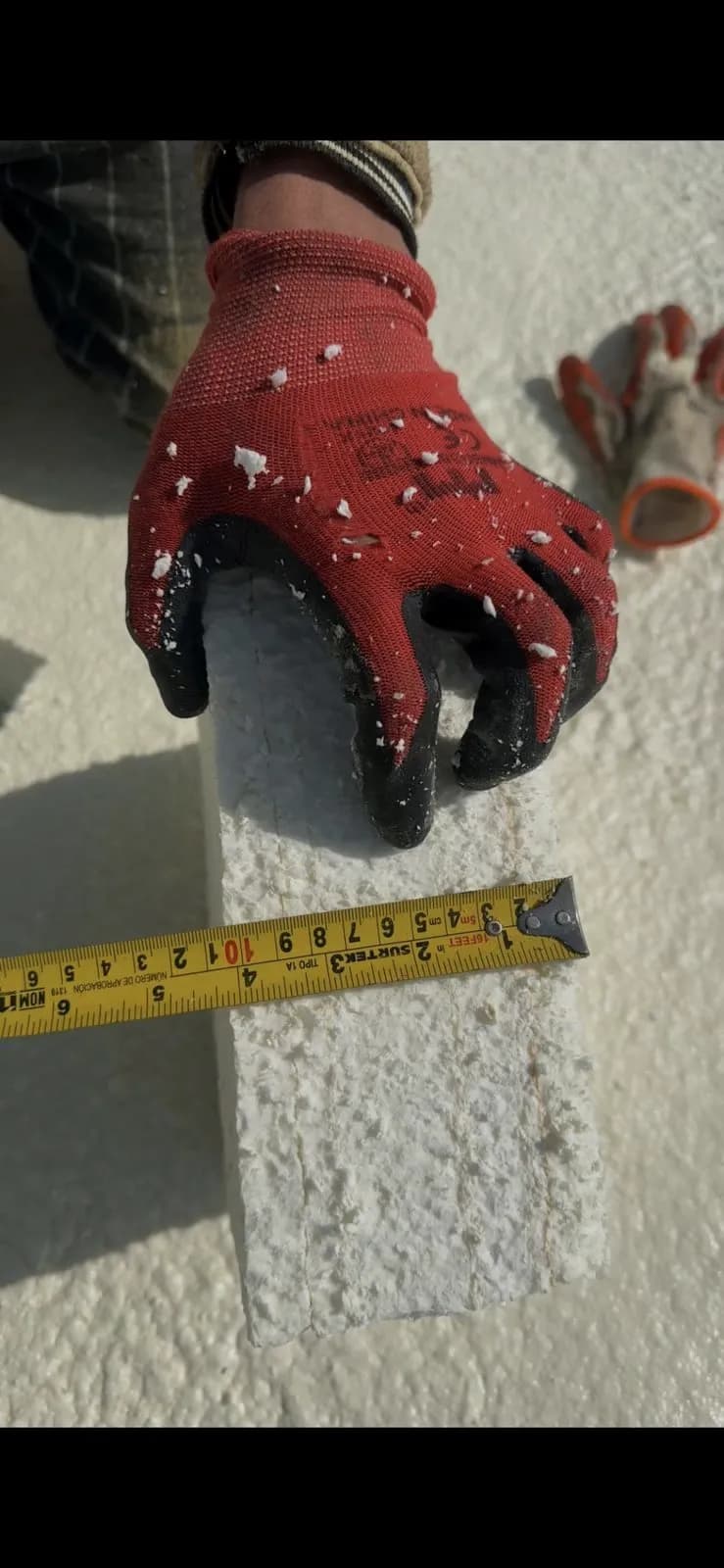 Measuring sprayed foam thickness with a tape during quality checks